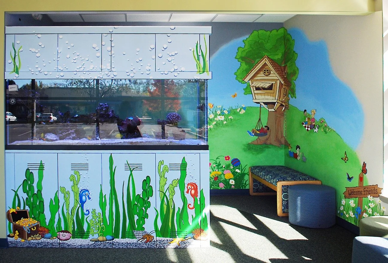 Colorful indoor play area with an aquarium tank and ocean-themed murals, including fish, seaweed, and a treehouse with children on a swing.