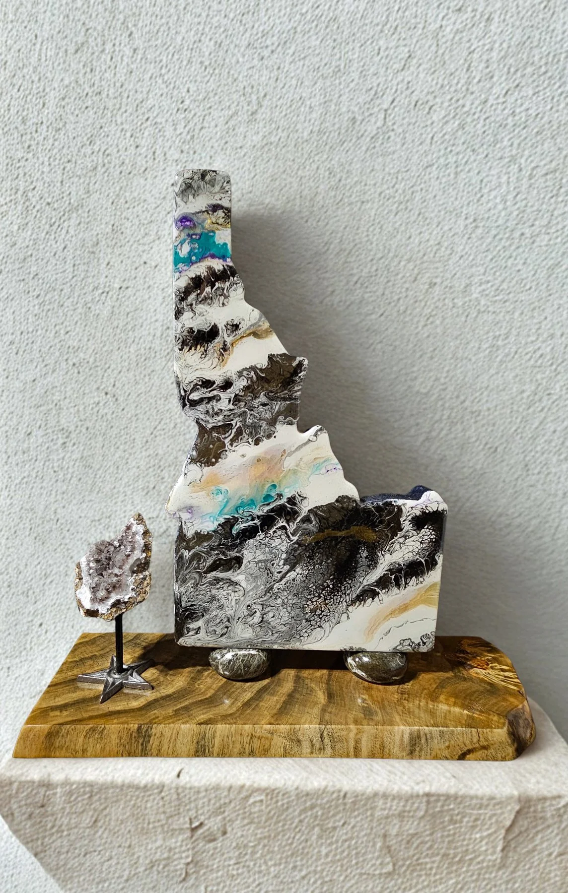 A decorative art piece consisting of a large, abstract marble sculpture on a wooden base, accompanied by a smaller rock on a stand.