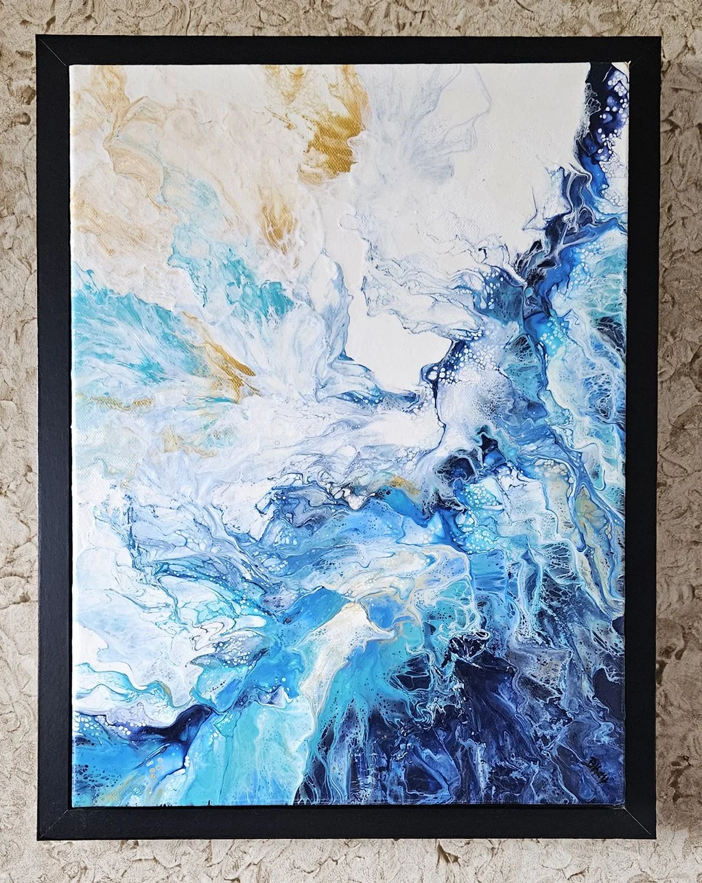 Abstract painting featuring swirling patterns in shades of blue, white, beige, and hints of black, framed in black, hung on a textured wall.