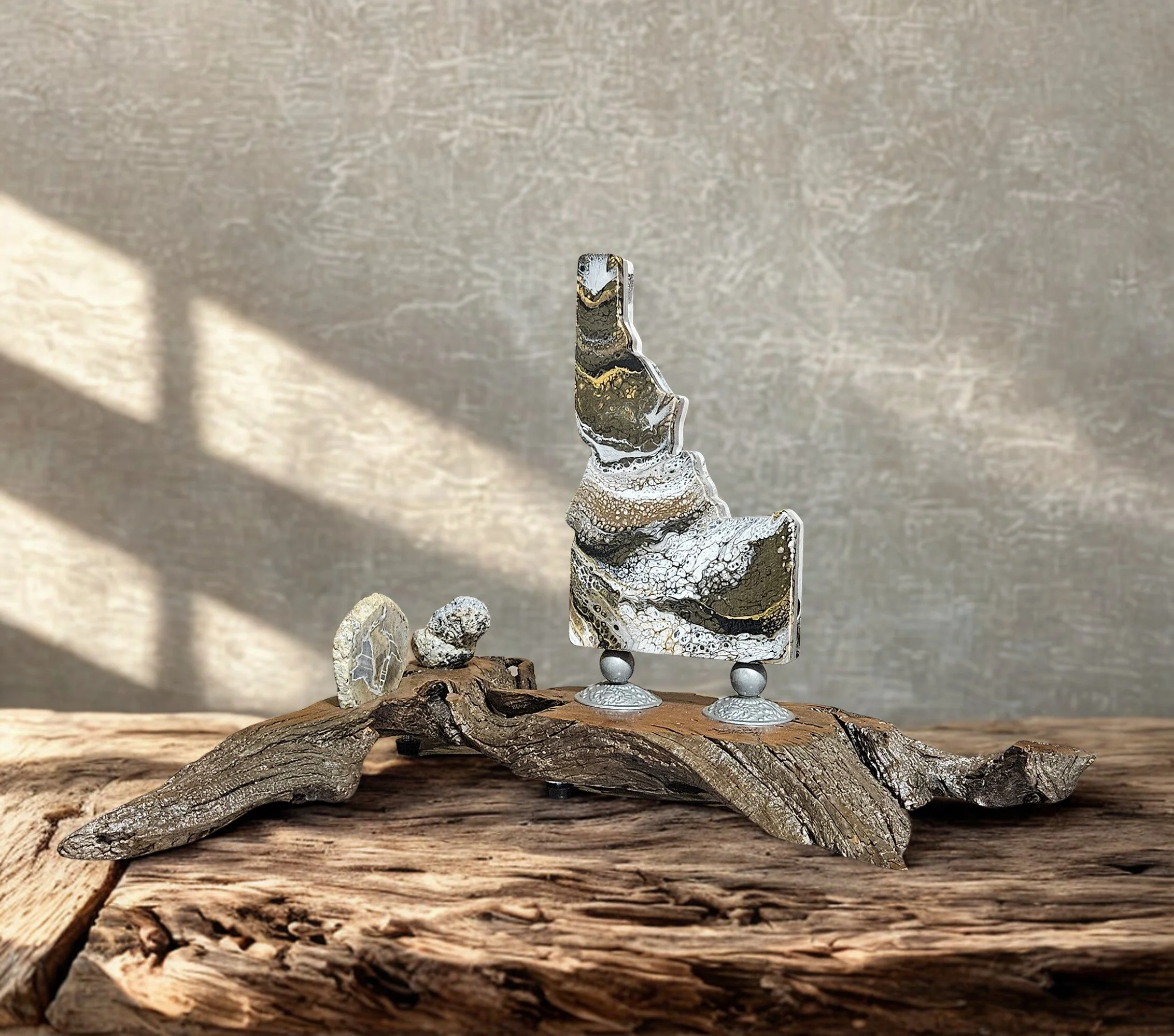 Artistic sculpture featuring abstract shapes and textures, mounted on a wood base with a neutral background.