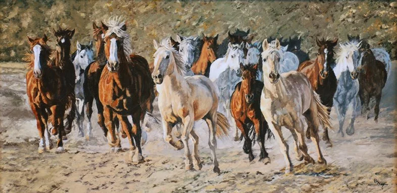 A group of horses running together on a dirt path with a natural background.