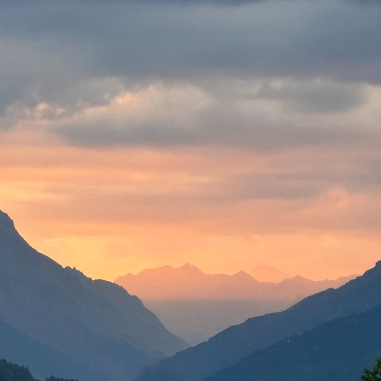 Mountain landscape at sunset with clouds and orange sky