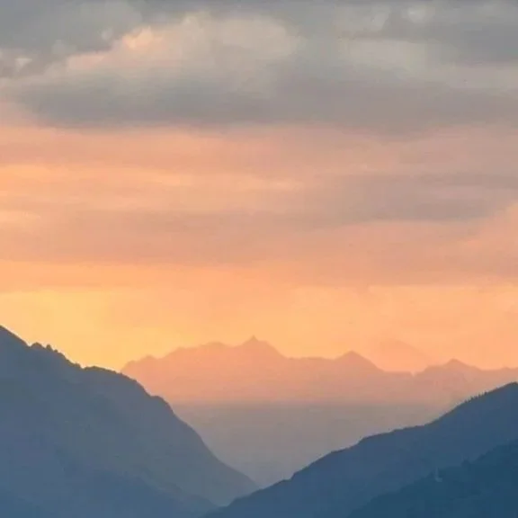 A sunset over a mountain range with colorful sky and distant peaks.