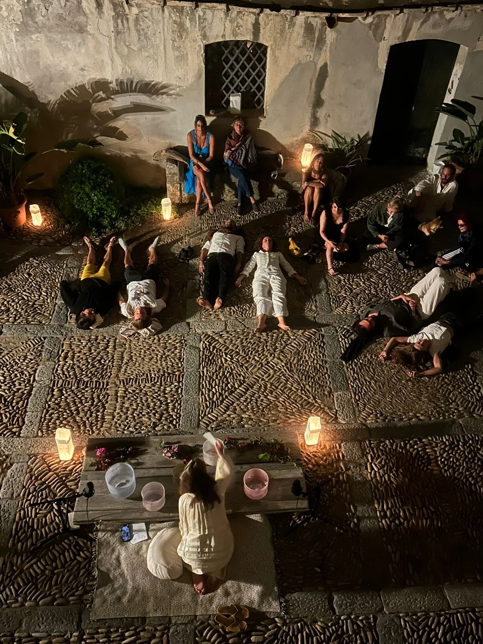 Guests lying on the ground in a relaxing pose during a piano and crystal sound experience in sicily
