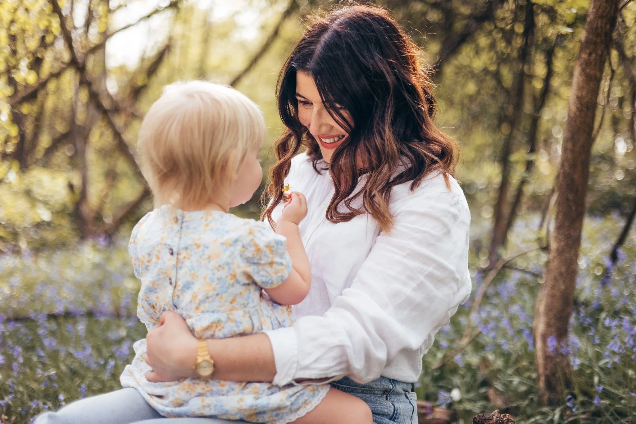 Mother and daughter sharing a cuddle among the bluebells in an Essex country park.