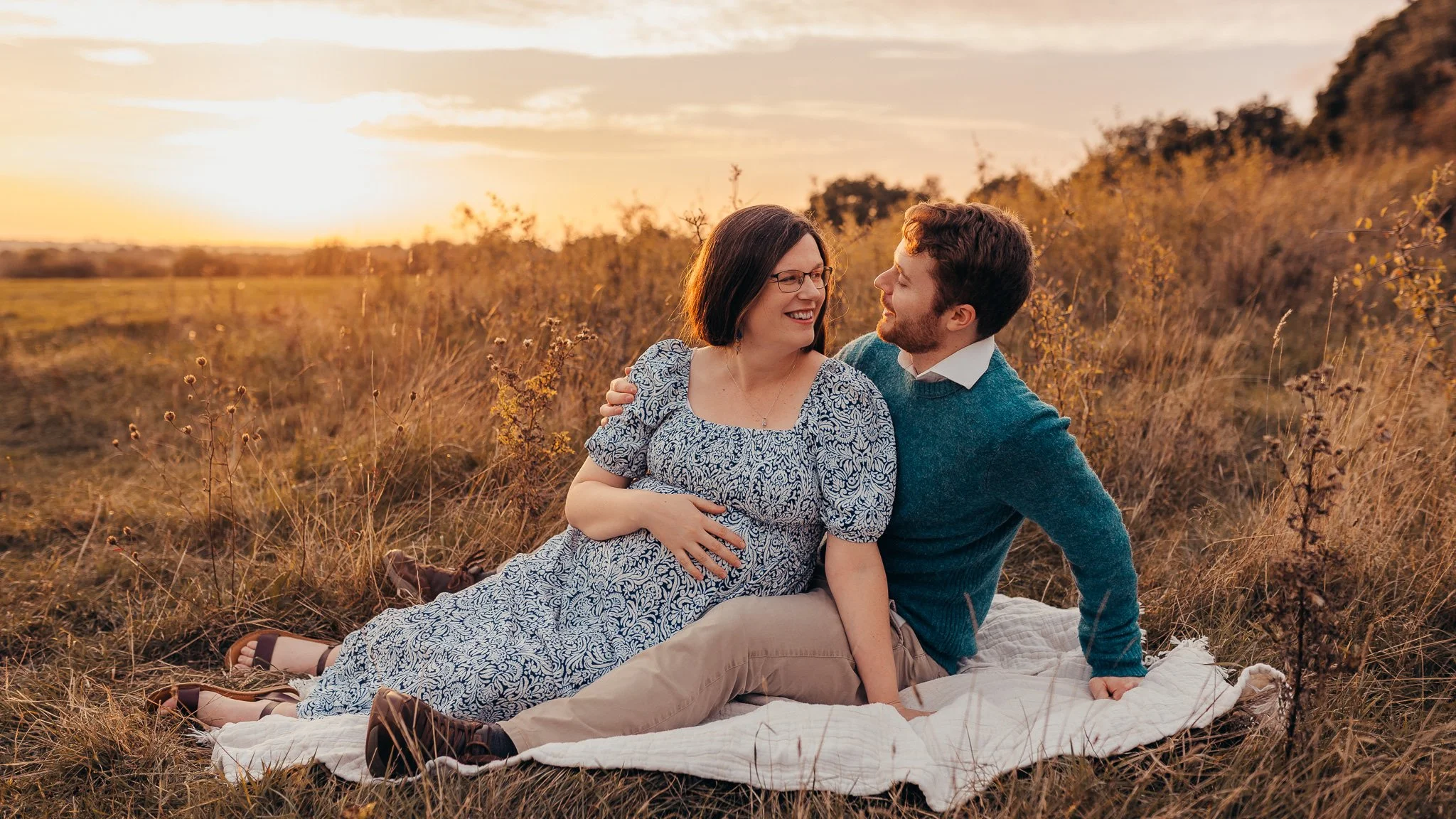 First time parents to be cuddling during a golden hour maternity photoshoot in an Essex country park