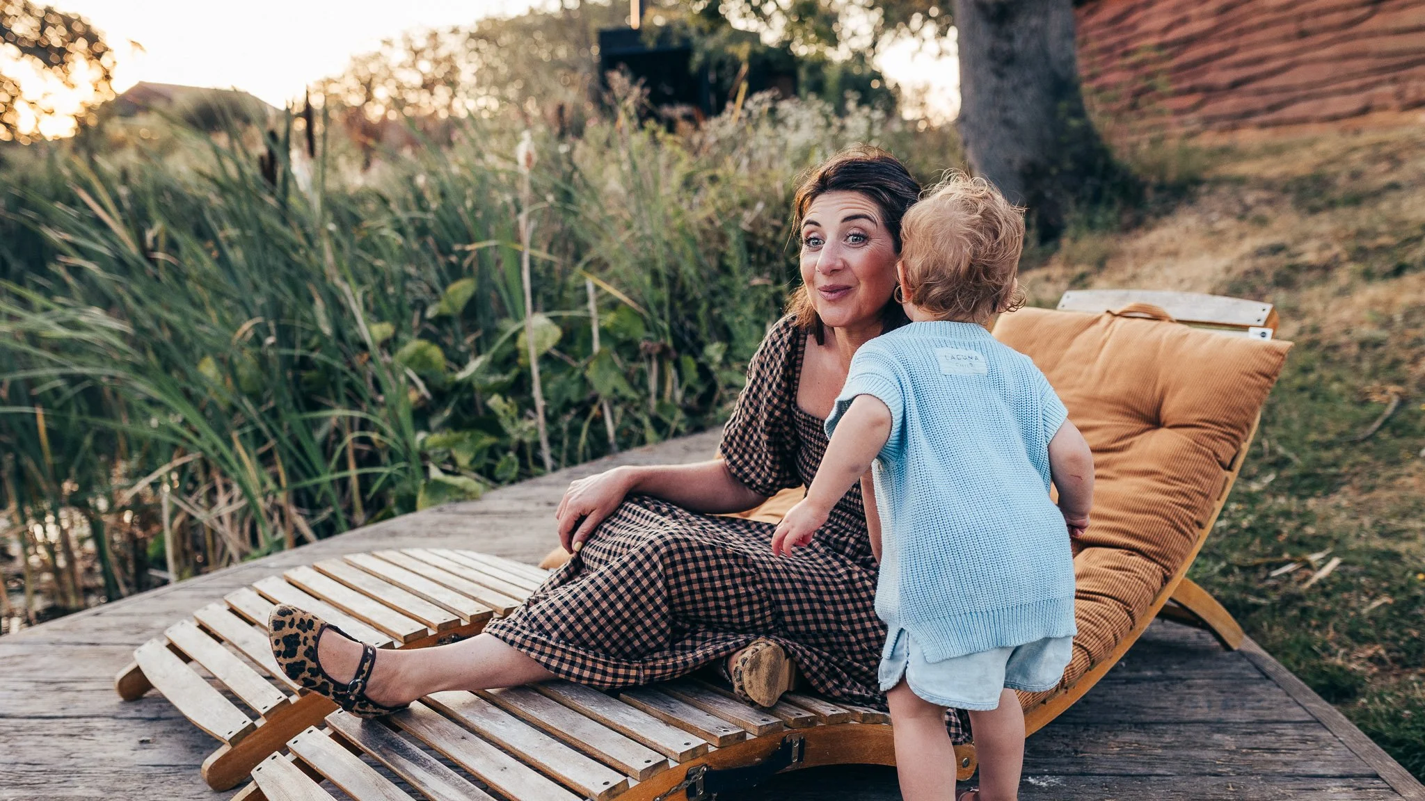Child whispering to her mum while relaxing on a lounger during golden hour.
