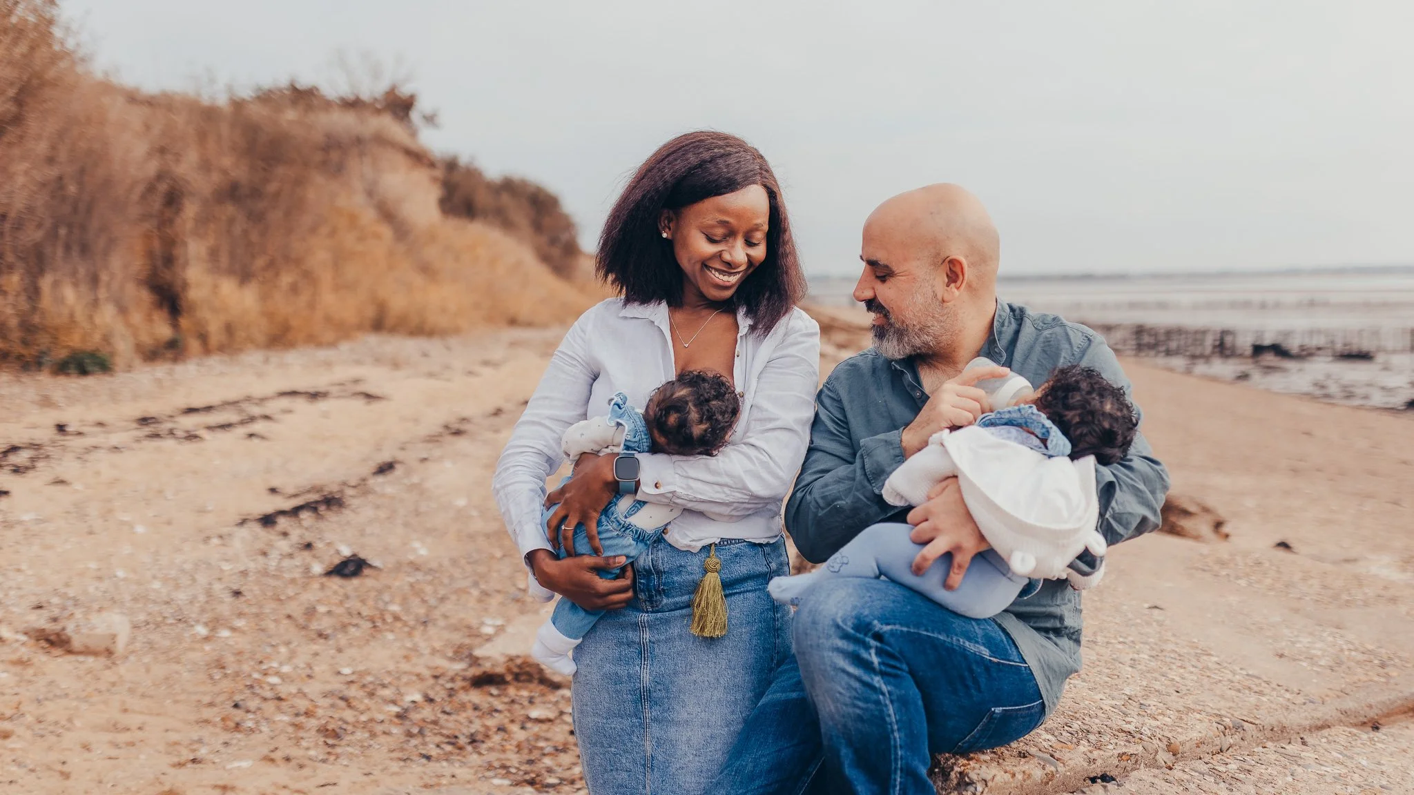 New parents feeding their baby twins during a photshoot at an Essex beach.