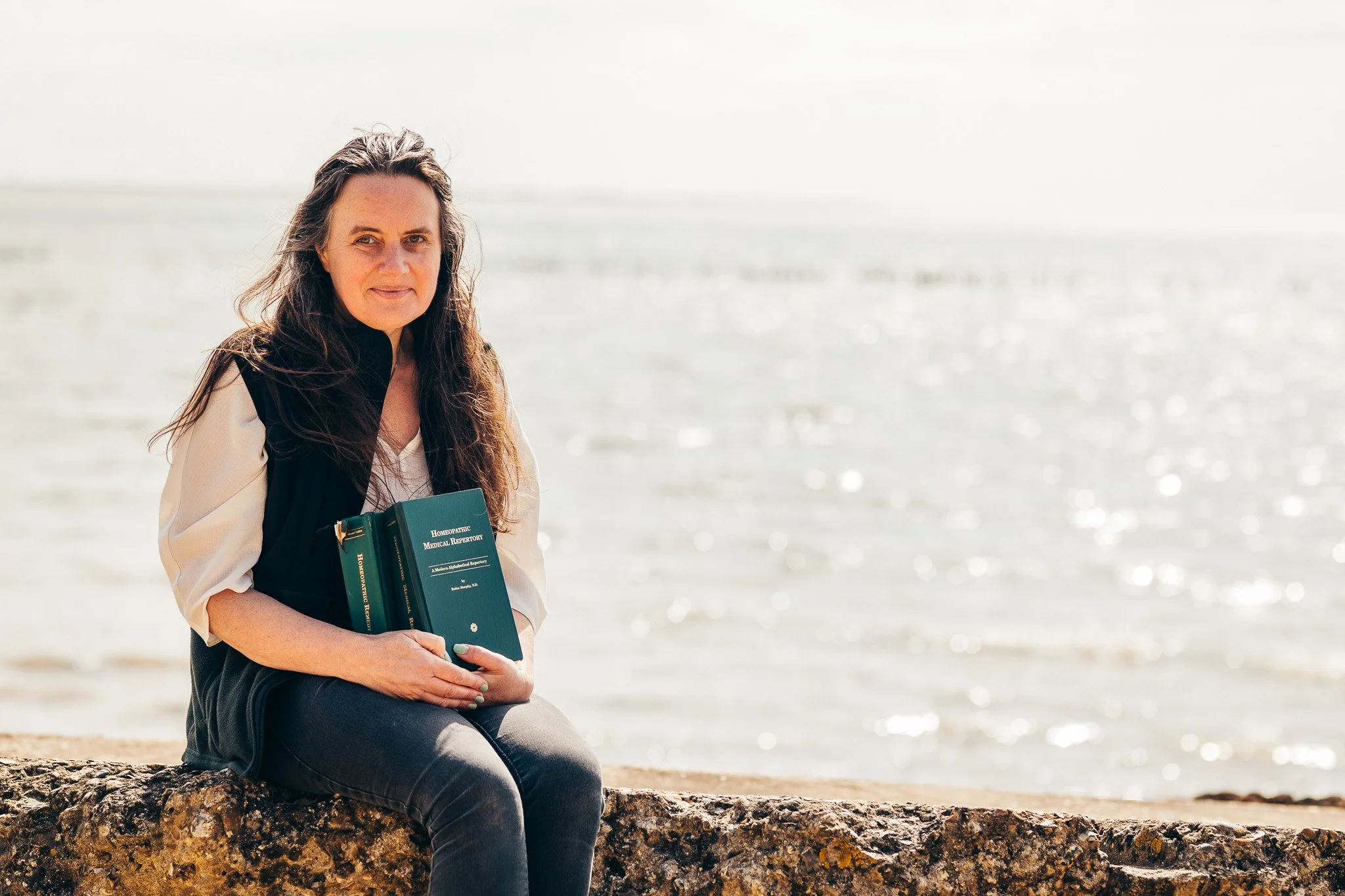Homeopath sitting at an Essex beach during a relaxed personal branding photography session on a spring morning.