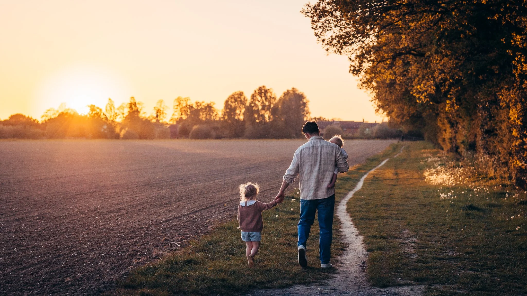 Family walking hand in hand into the sunset during an evening outdoors in Essex.