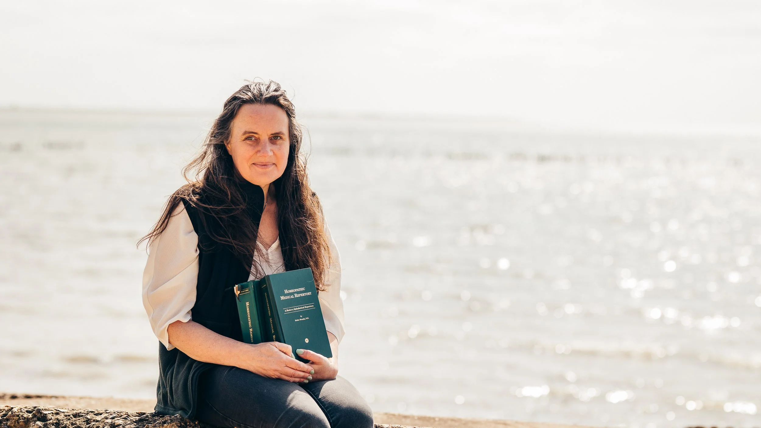 Homeopath sitting at an Essex beach during a relaxed personal branding photography session on a spring morning.
