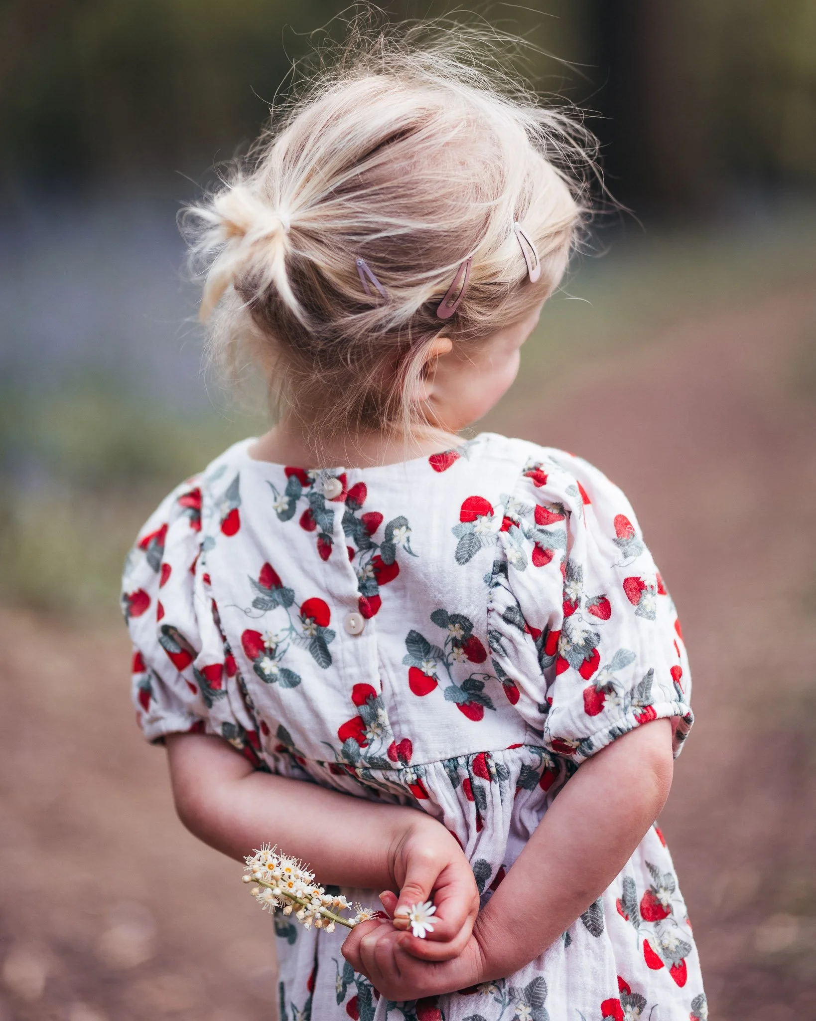 Child holding a flower she picked while exploring an Essex country park.