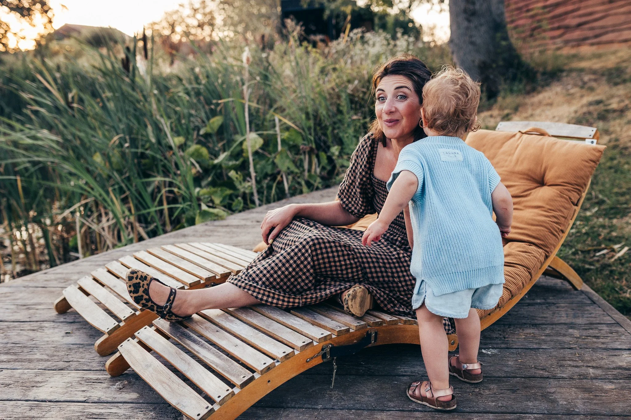 Toddler whispering to her mother during an outdoor photoshoot at The Lodge Essex during golden hour
