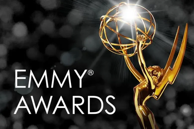 The image shows the Emmy Award statue with a bright light and a starburst effect at the top of the statuette. The words 'Emmy Awards' are displayed to the left, with a black and gray blurred background.