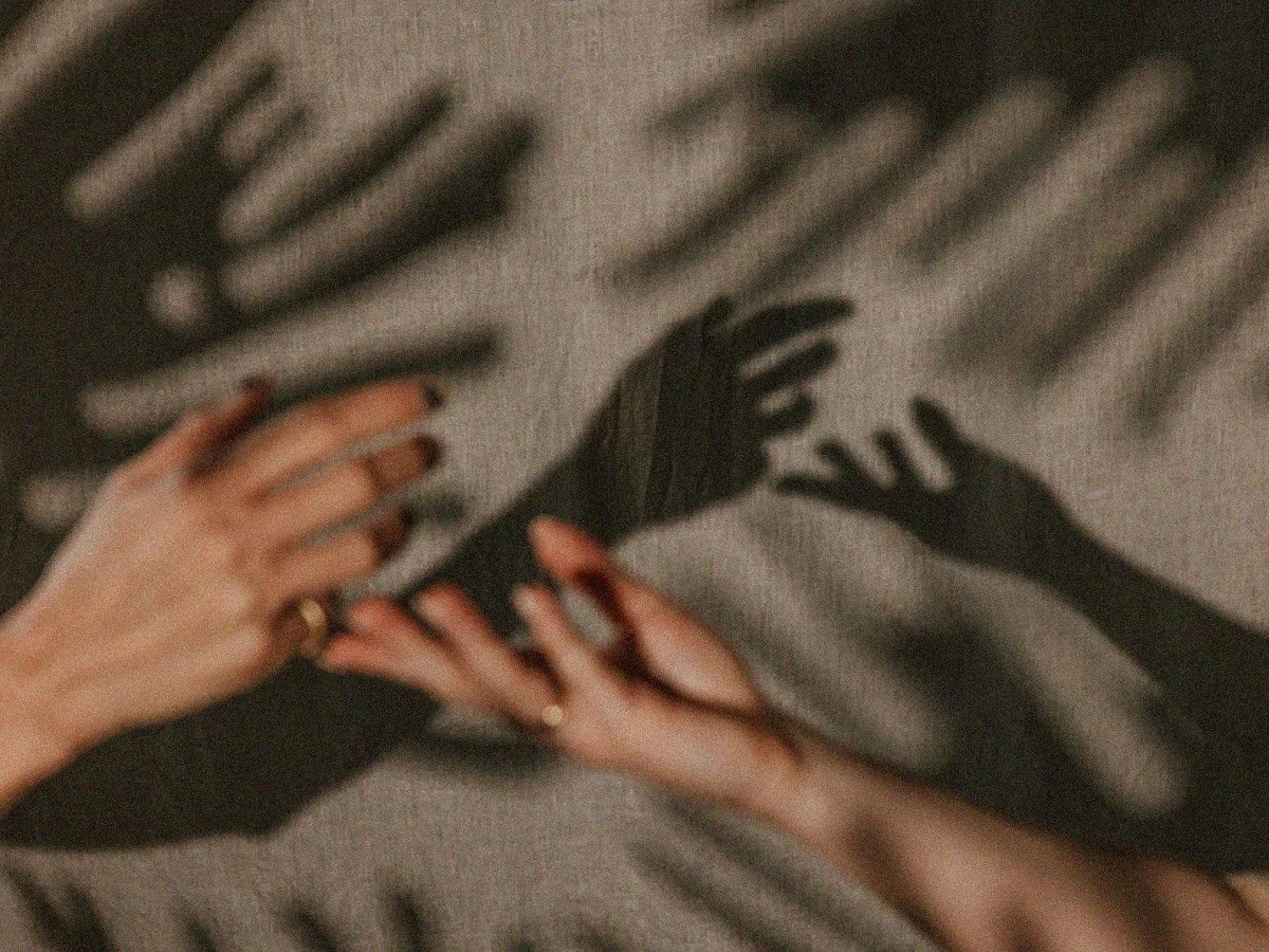 Shadow of two hands on a textured surface with blurred lines in background.
