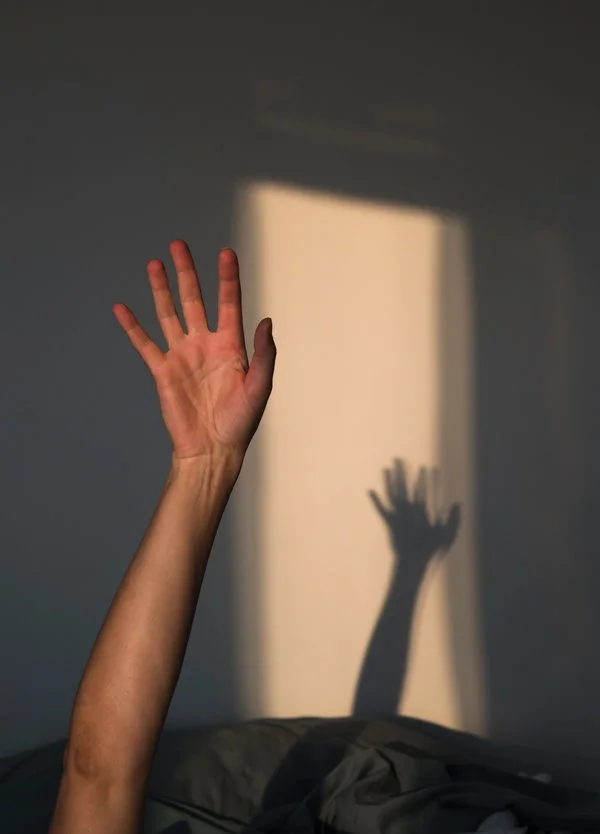 Hand reaching in shadows
