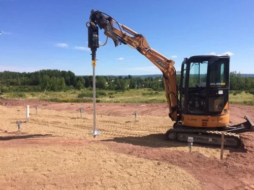 On-site screw pile installation using hydraulic equipment in Buffalo area.