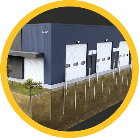 Industrial warehouse with multiple large garage doors, surrounded by a fenced yard, under a partly cloudy sky.