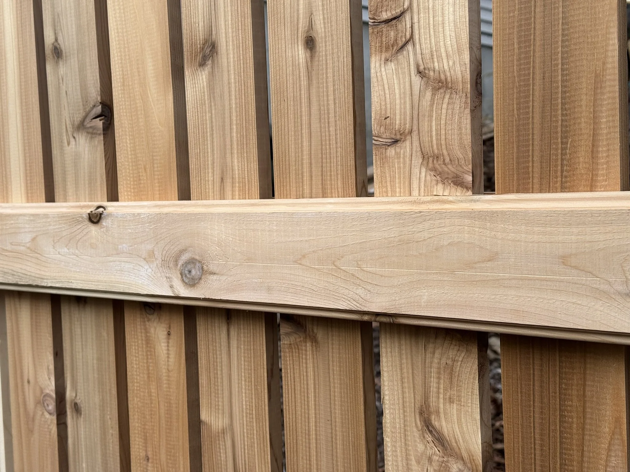 Close-up of a wooden fence with vertical planks and a horizontal support beam.