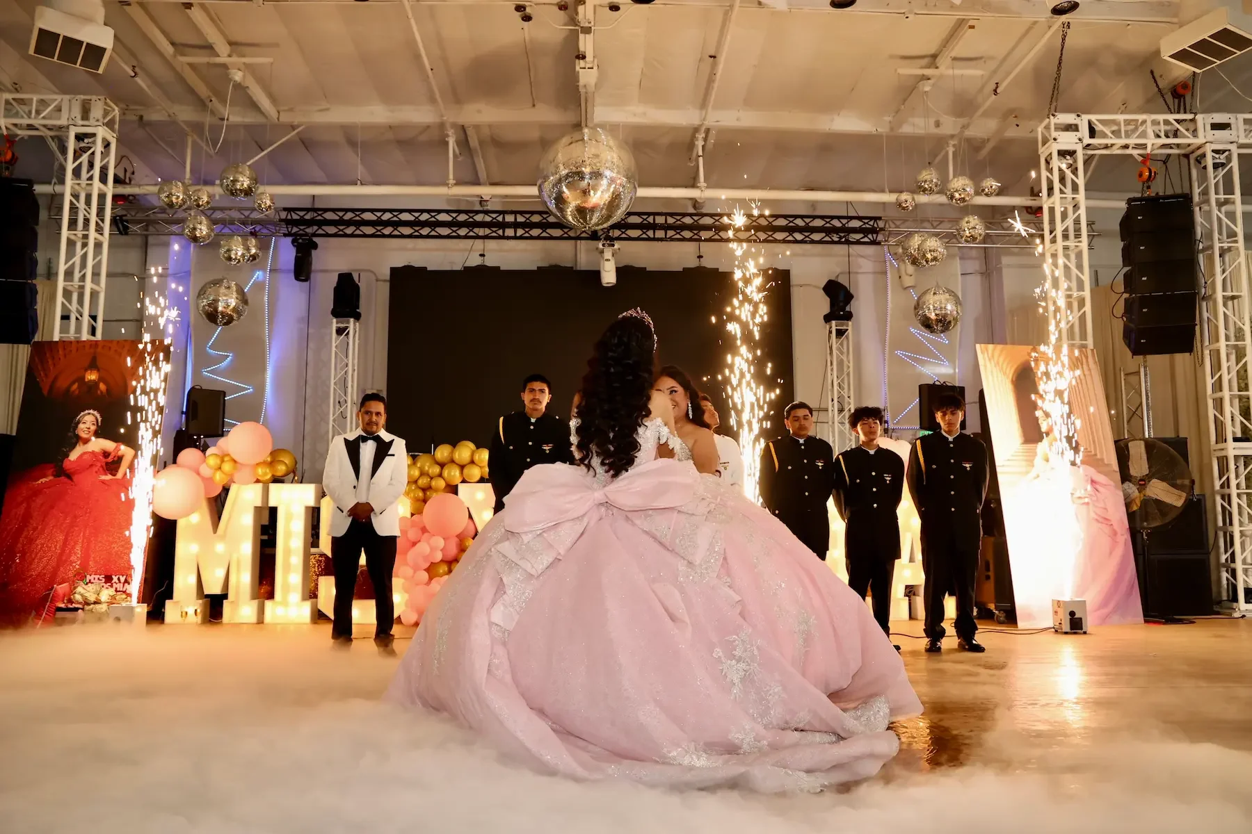 Quinceañera celebration in The QD Venue grand ballroom with sparklers and stage lighting.
