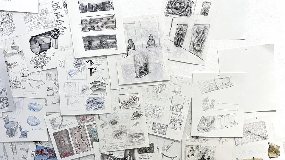 Various sketches, and drawings related to design or art projects pinned or taped to a wall, including architectural and artistic renderings.