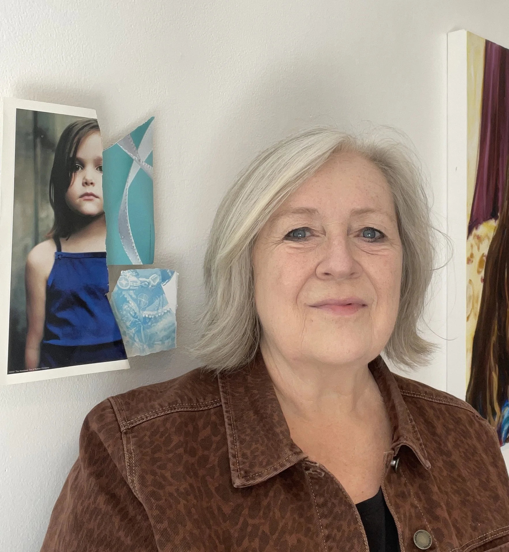 Woman with shoulder length gray hair wearing denim jacket standing in front of a paper installation art piece