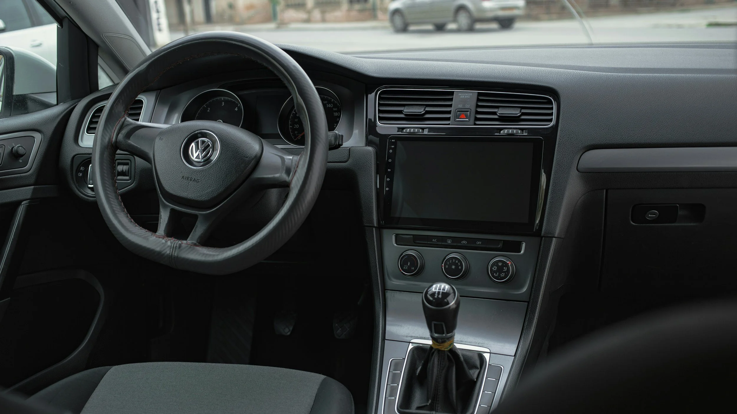 Interior of a Volkswagen car showing the steering wheel, dashboard, gear shift, and touchscreen display.
