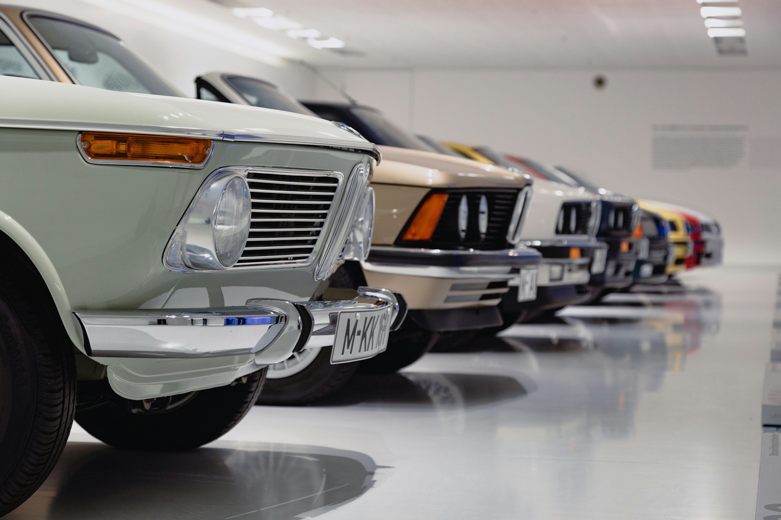 Lineup of vintage cars in a showroom, displaying sleek and classic designs.