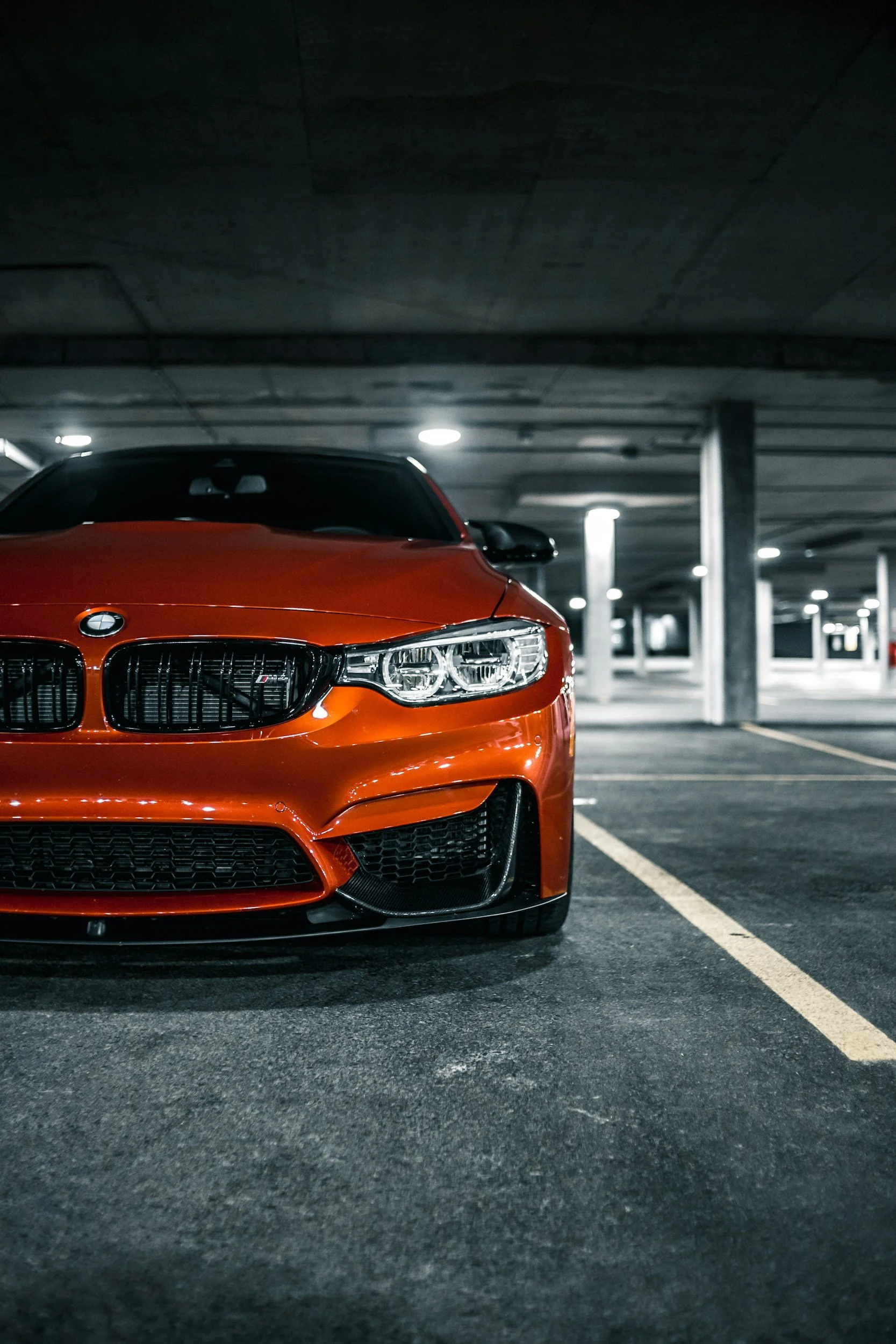 Red sports car parked in an empty underground parking garage at night.