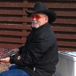 A landscape of trees and grassy fields during sunset or sunrise with a clear sky.