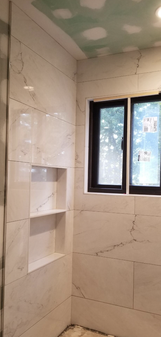 Marble-tiled bathroom shower with built-in shelf and window