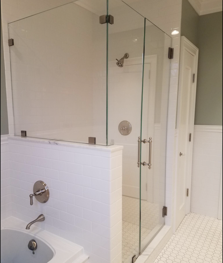 Bathroom with a glass-enclosed shower and a bathtub, white subway tile walls, a showerhead, faucet, and knob, light gray walls, a white door, and honeycomb-patterned white floor tiles.