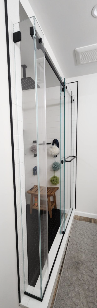 Glass shower enclosure with black hardware in a modern bathroom.