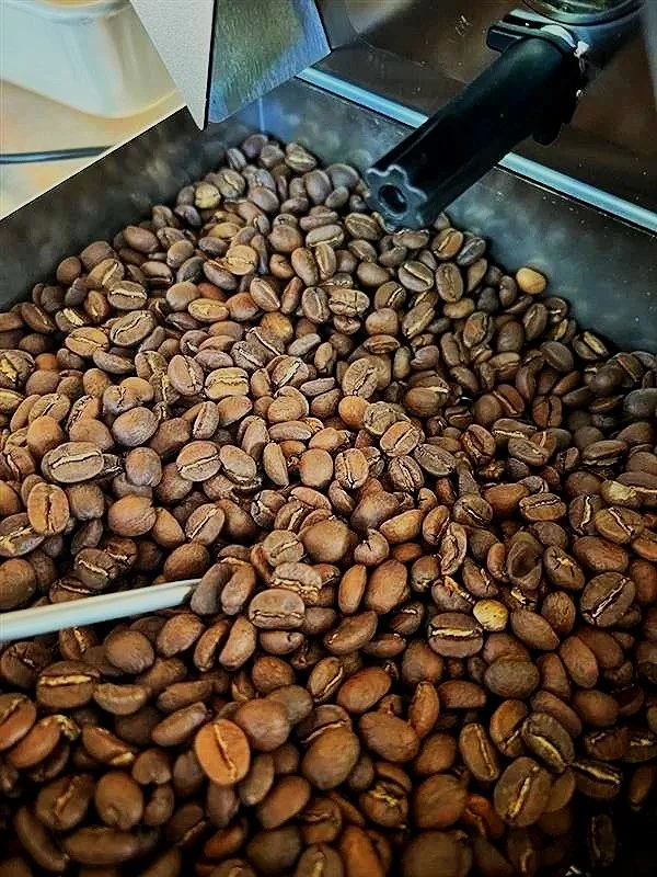 Close-up of roasted coffee beans with a coffee roasting machine burner at the top.