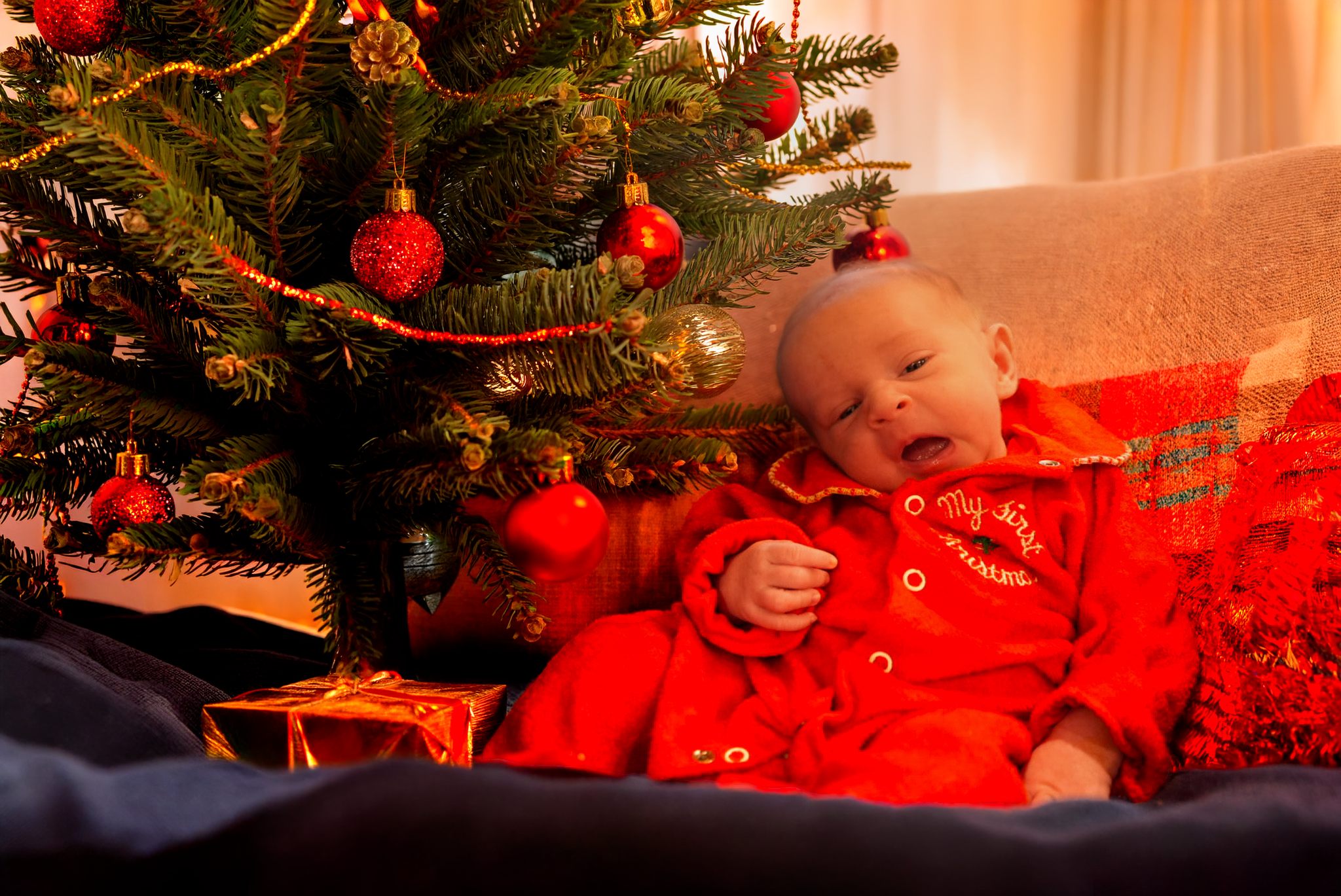 Warm, cozy Christmas family portrait featuring a smiling family in matching pajamas gathered around a decorated tree and fireplace. This holiday photo captures authentic joy, connection, and festive traditions perfect for seasonal cards and keepsakes