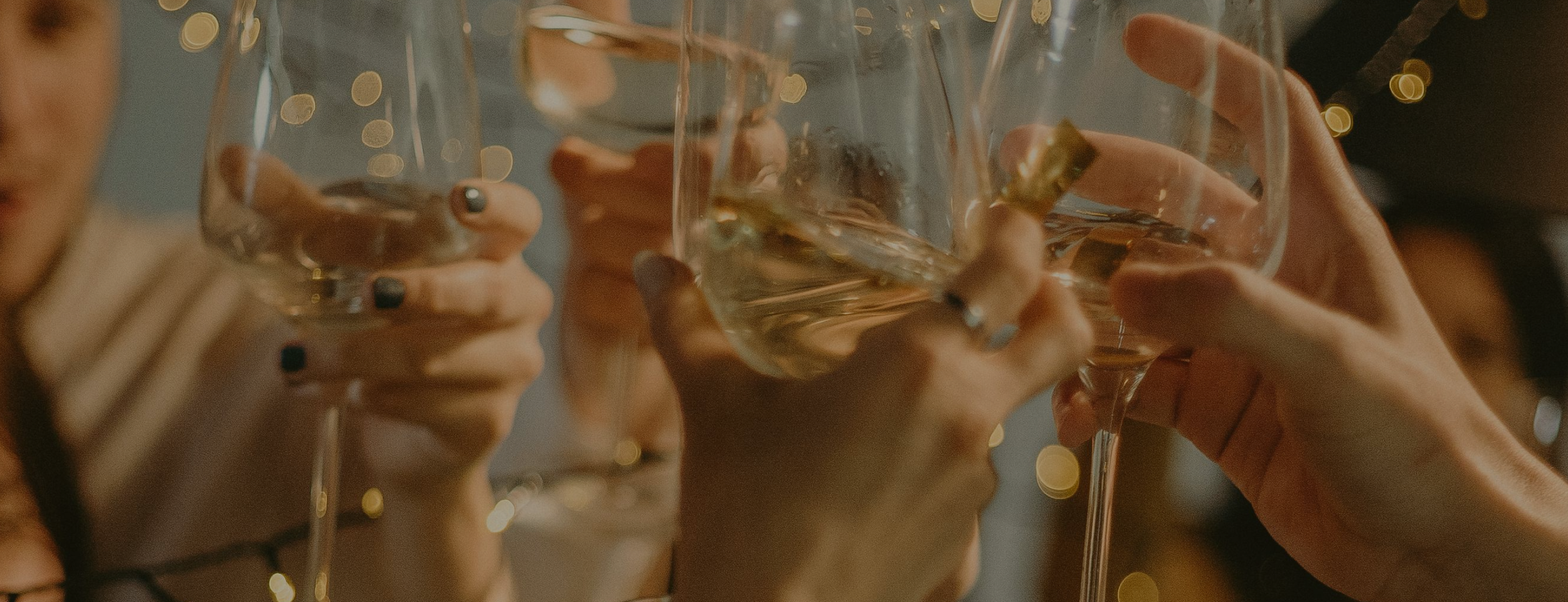 People clinking glasses of white wine in a toast at a celebration or gathering.