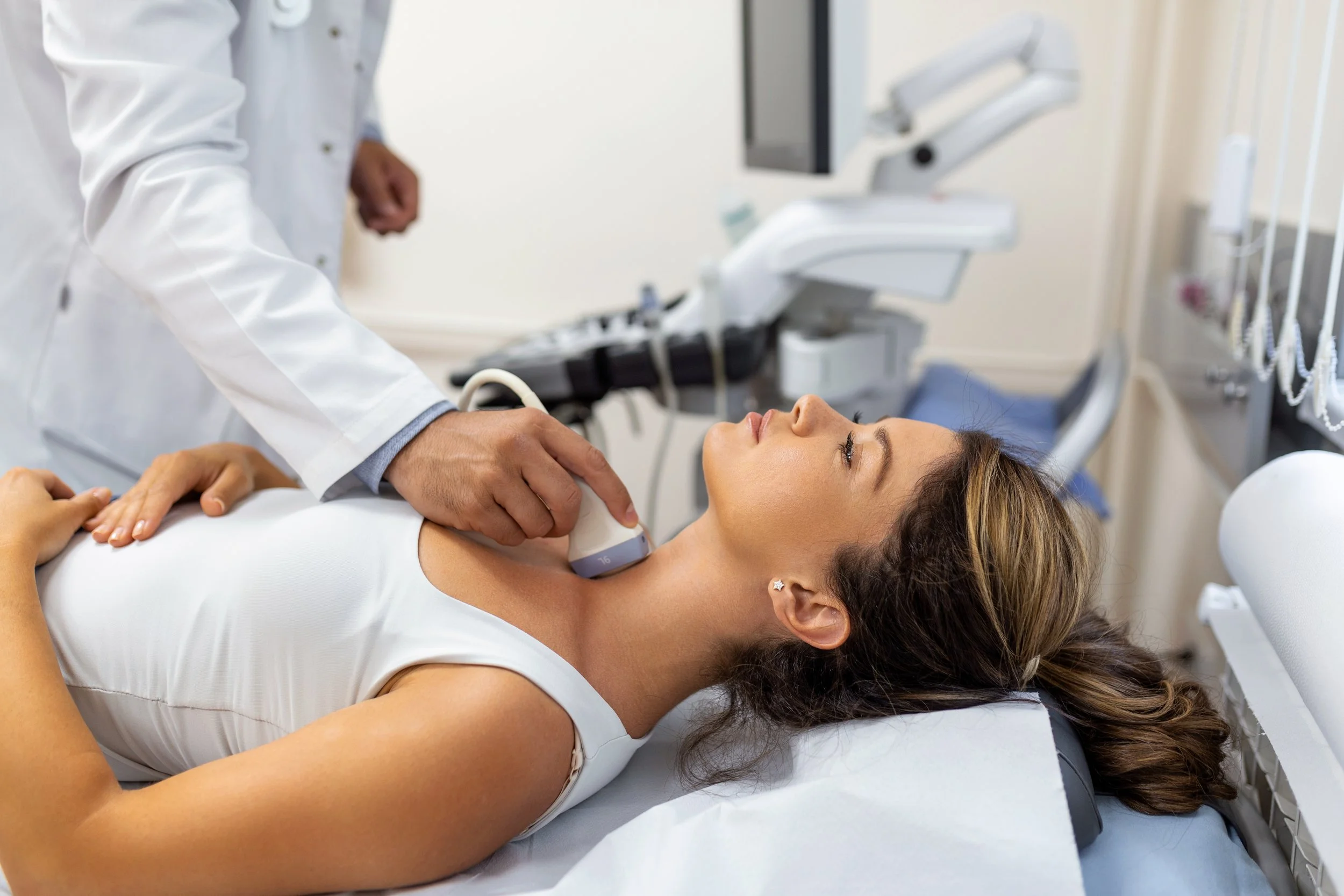 Medical professional performing an ultrasound on a woman lying on an examination table in a medical clinic