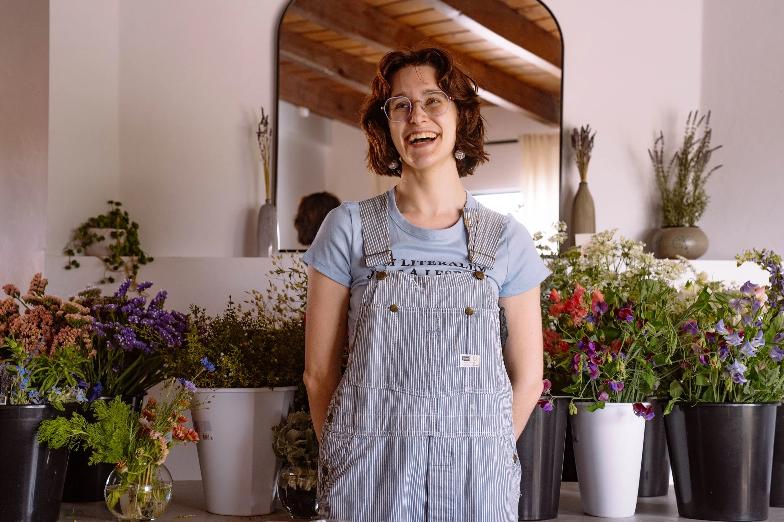 Pigeon and Poppy founder Abby smiling standing in front of buckets of flowers.