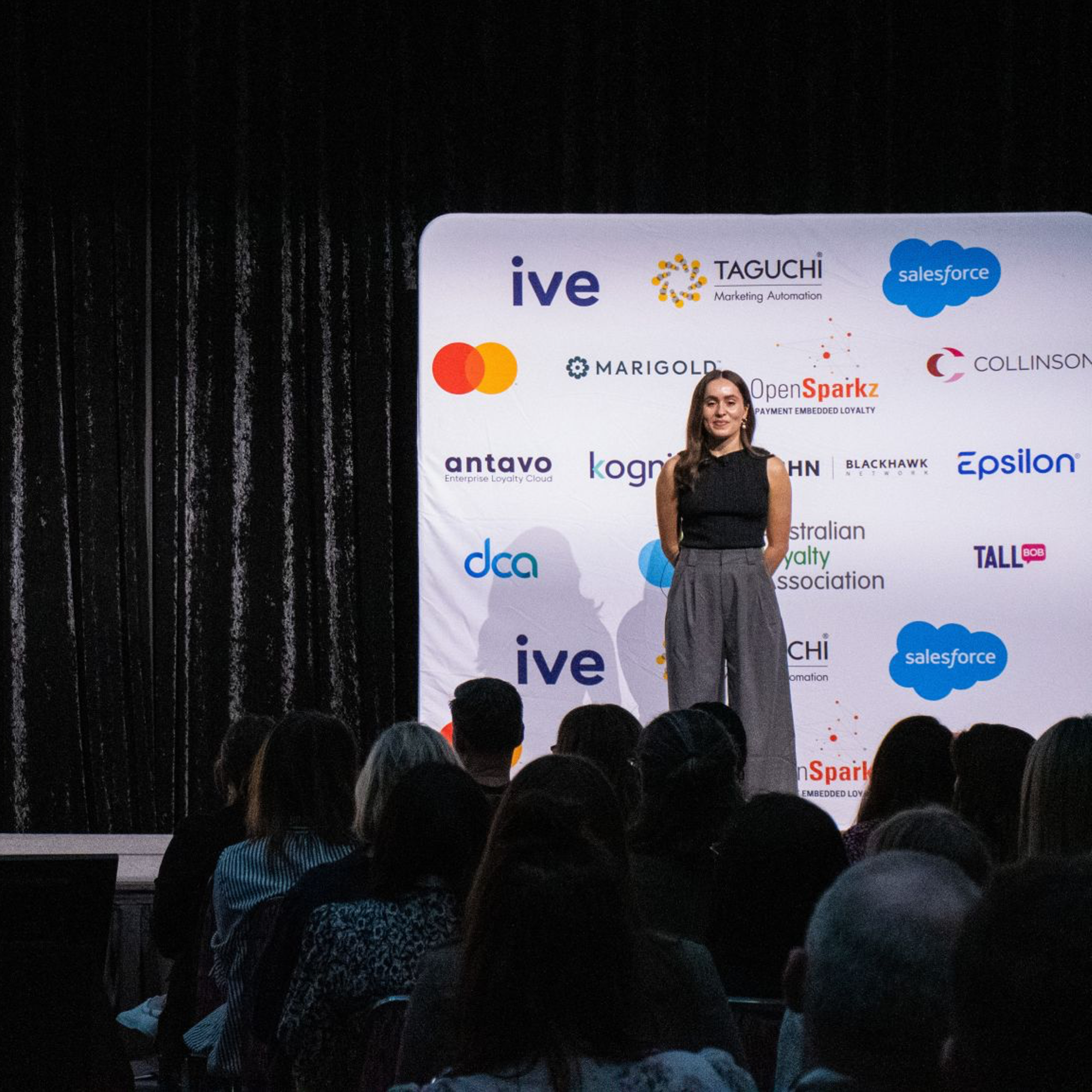 Thinking People at the Australian Loyalty Association with a backdrop displaying logos of various companies and au audience seated in front