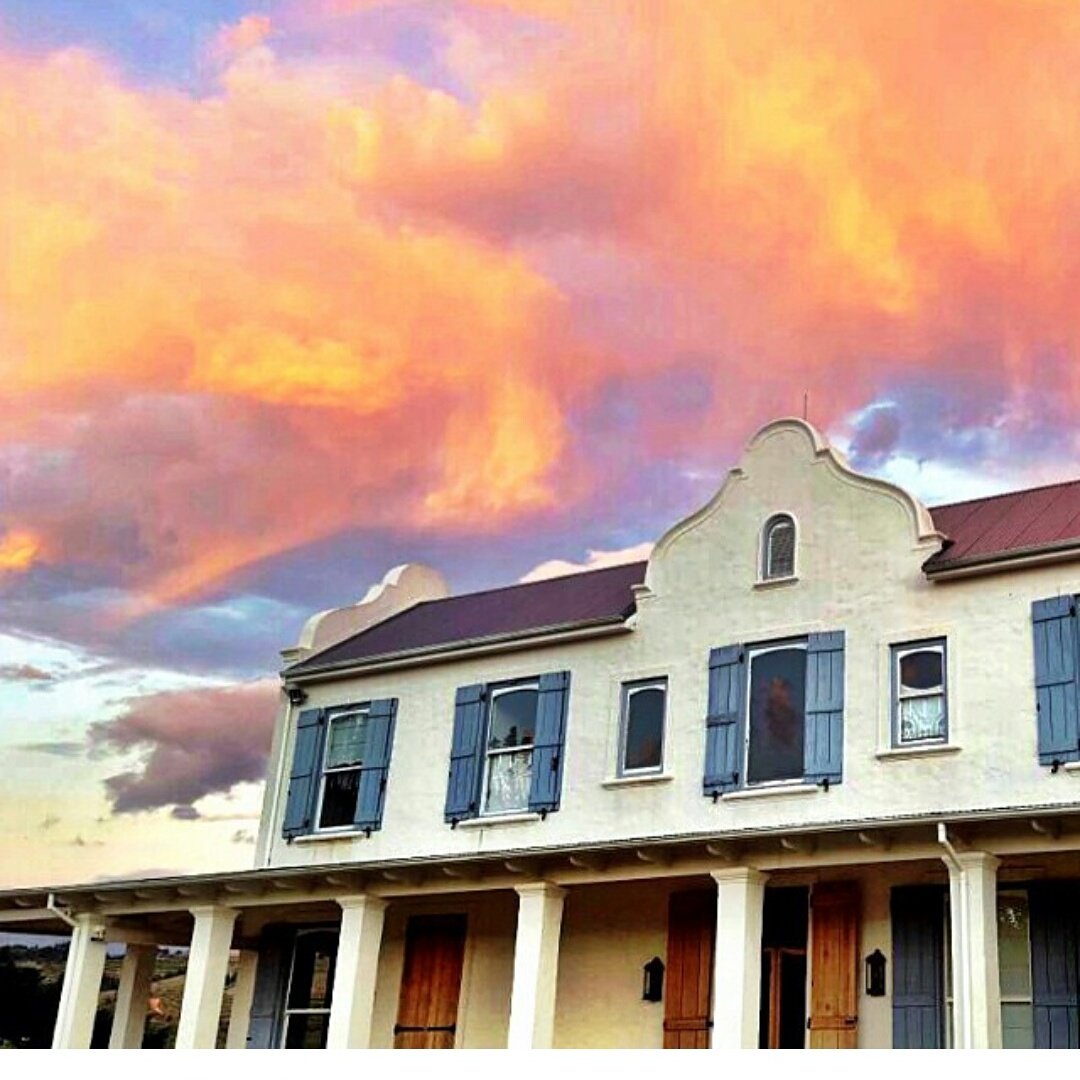 The Oneiric homestead under a colourful sunset sky with orange and purple clouds at sunset.