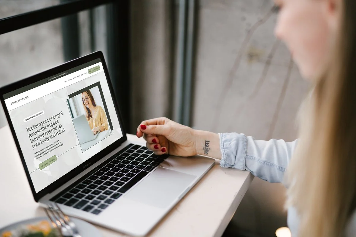A laptop displaying a Squarespace website design for health and wellness professionals, with green, white and beige sections and a smiling practitioner at a computer.