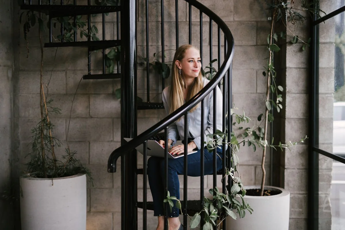 Yolie Stephenson web designer and copywriter working in an Auckland cafe wearing a light denim and dark blue jeans