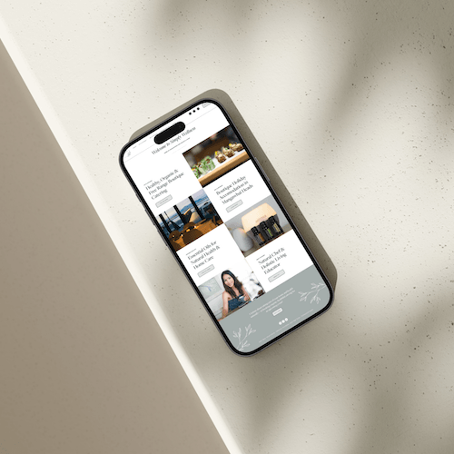 A smartphone on a light surface displays a health and wellness website design with images and text blocks in a minimalist layout.