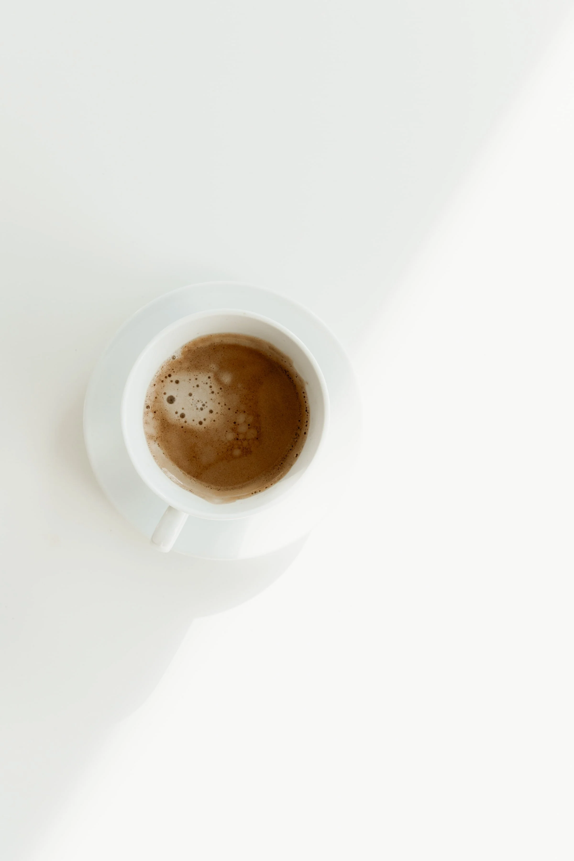 A cup of espresso on a saucer beside papers—perfect fuel for planning your Squarespace website design in Auckland.
