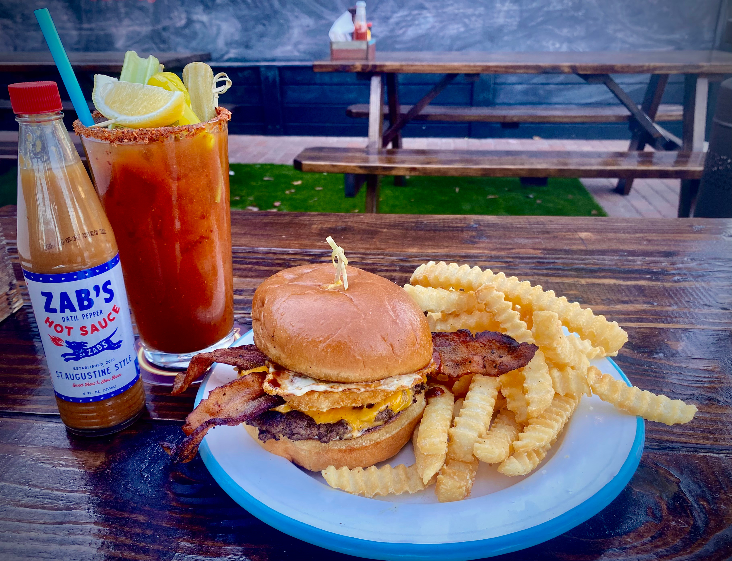 The Fillin' Station cheeseburger with crinkle cut fries, crispy bacon, and a signature Bloody Mary served on the patio.
