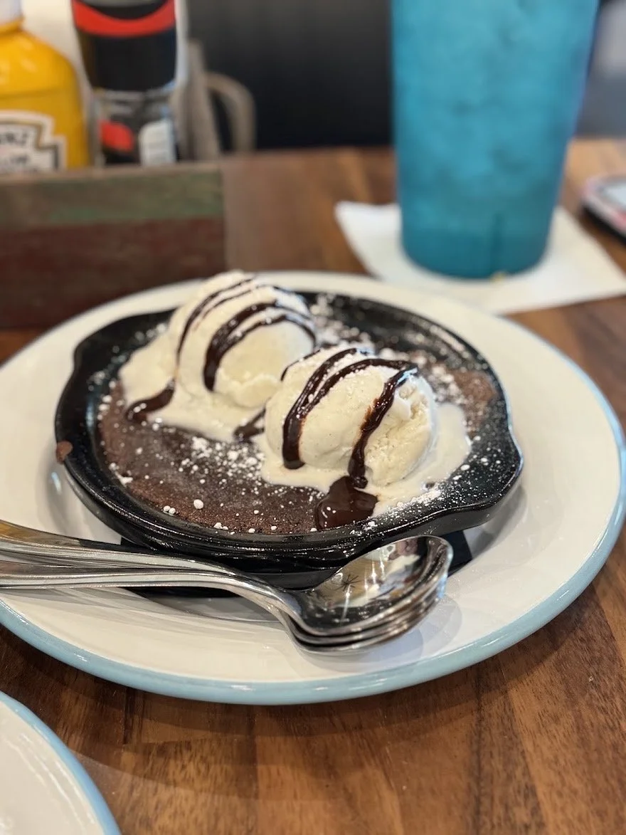 Warm skillet brownie topped with vanilla ice cream and chocolate drizzle at The Fillin' Station.