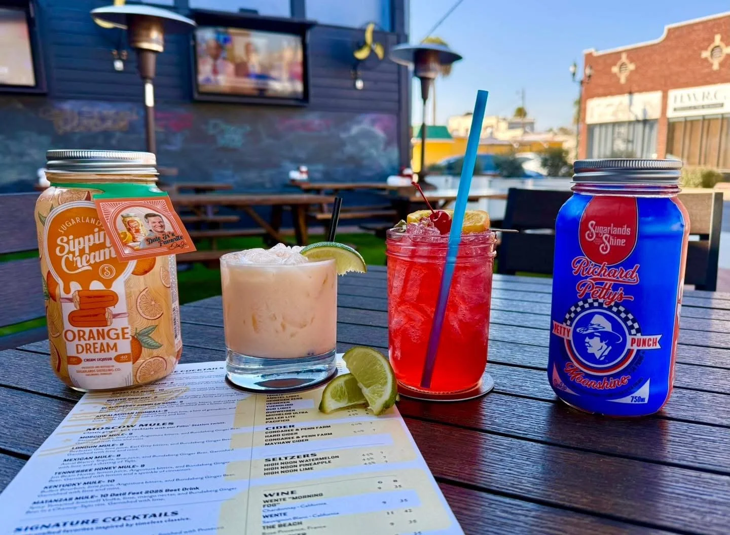 Signature cocktails and canned beverages served on the outdoor patio at The Fillin' Station in Palatka, Florida.