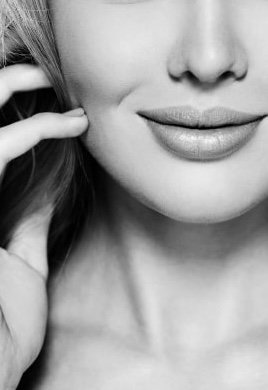 Close-up of a woman's face, focusing on her lips and part of her nose, with her hand near her cheek.