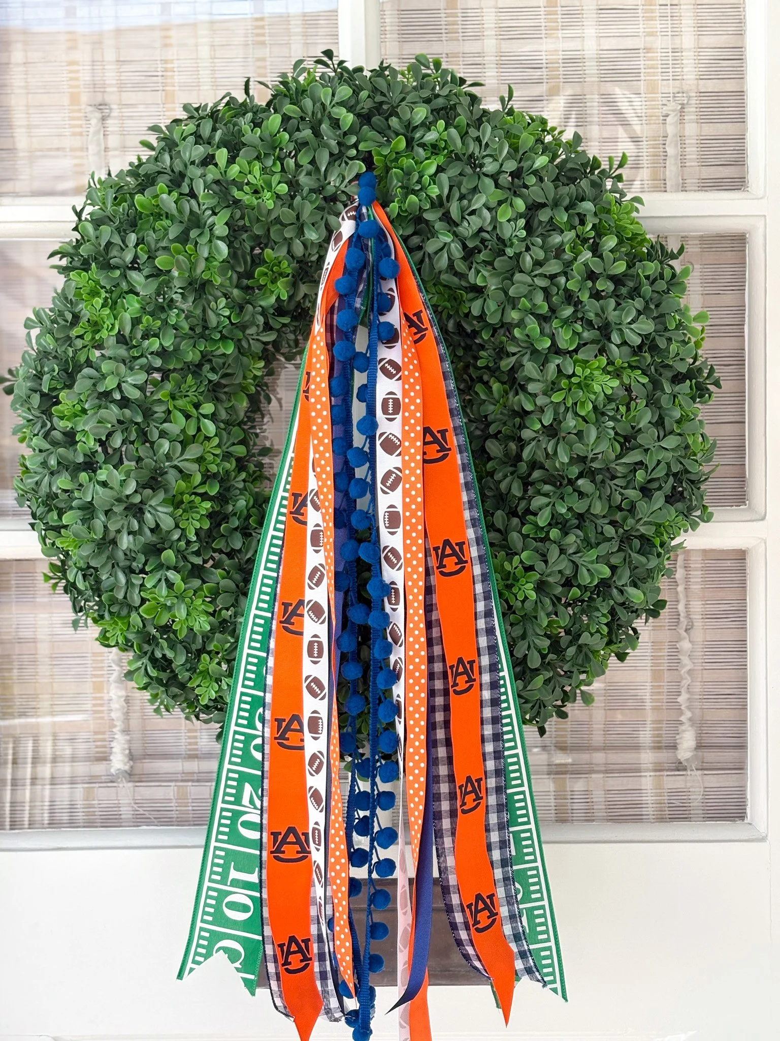 Green wreath decorated with Orange and blue University-themed ribbons and banners.