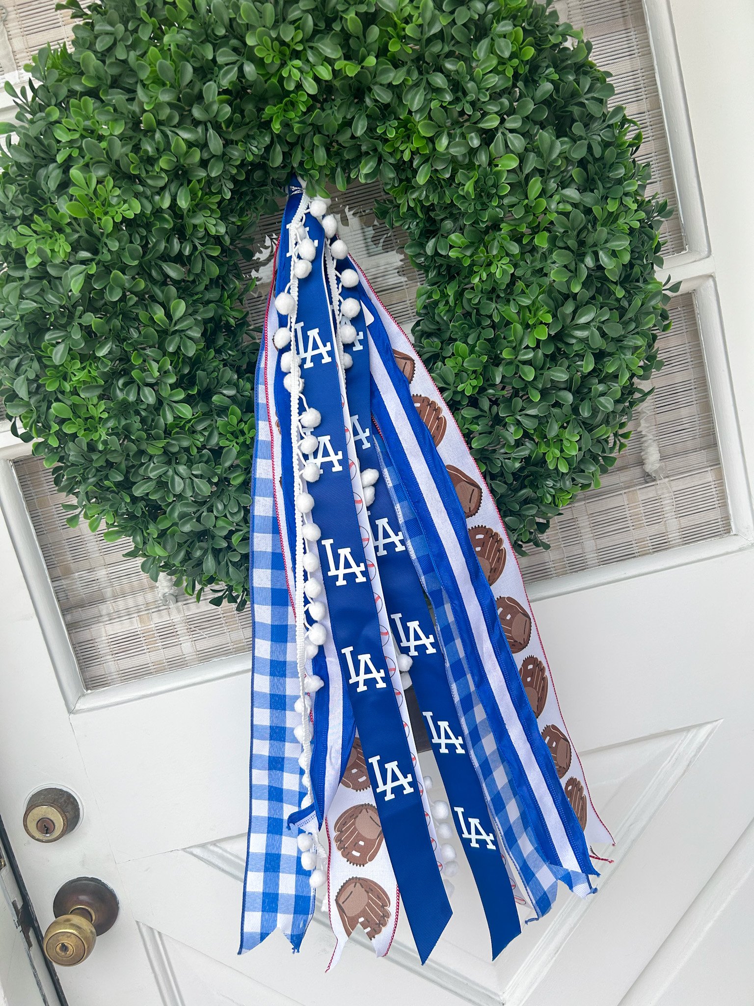 Decorative wreath with ribbons featuring Los Angeles baseball team and brown baseball glove patterns hanging on a front door.